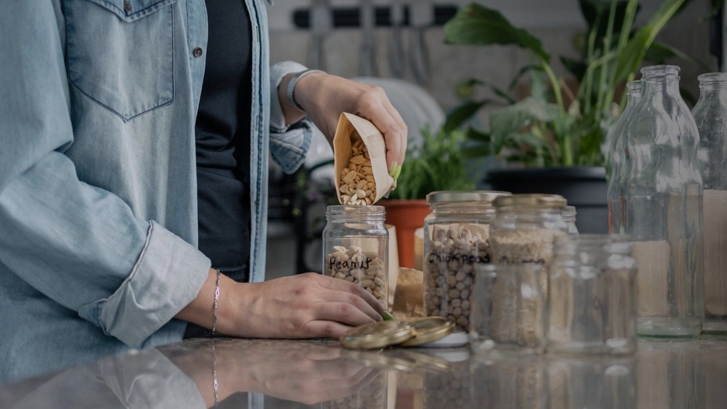 Person preparing food with jars and bottles on a reflective surface