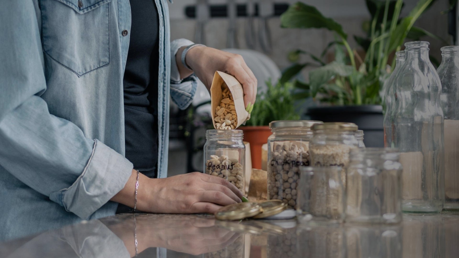 Person preparing food with jars and bottles on a reflective surface